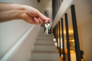 Hand holding house keys in a modern interior